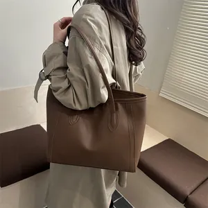 Grand sac cabas vintage marron foncé en similicuir porté à l'épaule par un mannequin