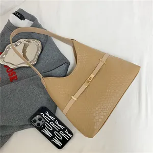 Gros plan d'un sac porté épaule marron clair avec texture tressée et boucle dorée
