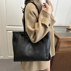 Sac cabas noir classique avec longues anses porté par un mannequin dans un décor épuré