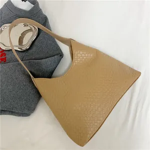 Détail de la texture en cuir tressé kaki et de la large bandoulière du sac fourre-tout