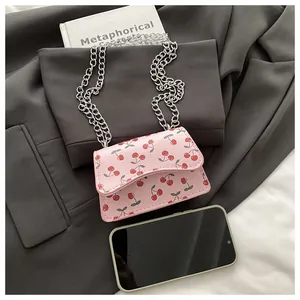 Detailed macro of a pink mini crossbody bag with cherry prints on a grey blazer