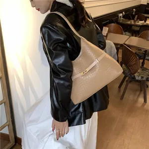 Détail du sac porté épaule kaki effet crocodile avec boucle dorée sur veste en cuir noir