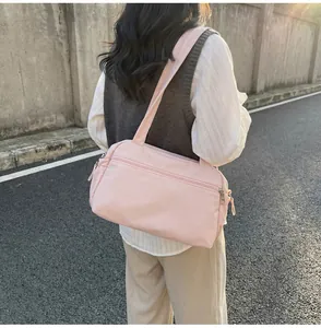 Detail of light pink canvas tote bag showing the front zipper pocket and strap on model