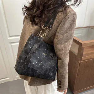 Chic black tote bag with star and moon patterns and gold chain straps on a model
