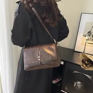 Borsa a tracolla vintage marrone scuro con fibbia dorata in un ambiente retrò elegante