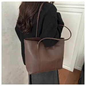 Détail d'un grand sac cabas marron foncé avec texture grainée et longues anses d'épaule