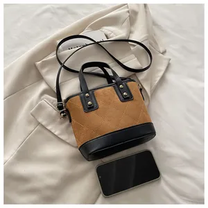 Détail du sac seau vintage en daim marron et cuir noir avec coutures losanges