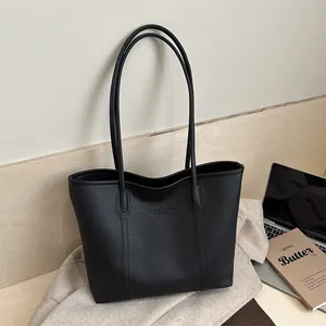 Detail of black lychee grain leather tote bag with embossed fashion text and long straps