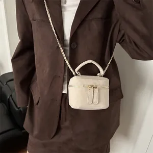 Retro crèmewitte emmer tas met gouden ritsen en kettingriem op een bruine outfit