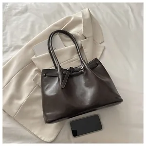 Close-up of matte dark brown leather tote bag with knotted strap detail and metal buckle