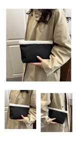Detail van zwarte getextureerde clutch met witte faux fur rand in lifestyle setting