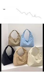 Group display of five colorful large capacity tote bags in nylon material with zipper detail