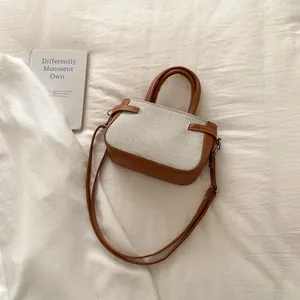 Top-down view of a small rectangular bag featuring brown leather and beige canvas contrast