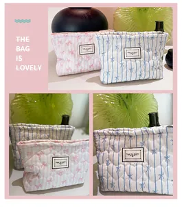 Dettaglio di pochette per trucchi trapuntate a cuore con stampe a fiocco e logo