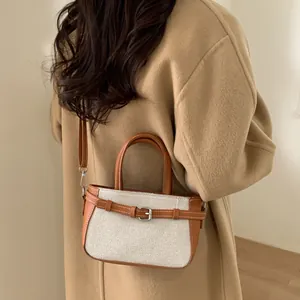 Detail of the woven canvas texture with brown leather straps and silver buckle finish