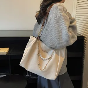 Elegant off-white tote bag with pearl chain and floral charm in a lifestyle setting