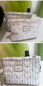 Dettaglio di pochette cosmetiche in cotone trapuntato con fiocchi e trama a righe