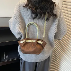 Borsa a mano marrone in pelle scamosciata con finiture verdi in una scena lifestyle