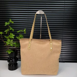 Close-up of light brown corduroy tote bag showing vertical texture and leather handle
