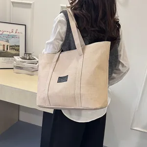 Grand sac cabas en toile de lin beige porté par un mannequin pour un look quotidien
