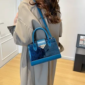 Blue crocodile pattern crossbody bag with metallic triangle buckle shown on model