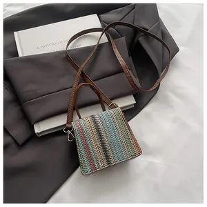 Detail of woven multi-colored striped mini square bag with brown leather strap