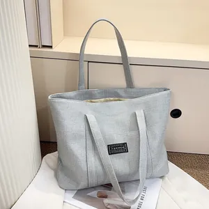 Détail du sac fourre-tout en lin gris tissé avec étiquette mode et doubles poignées