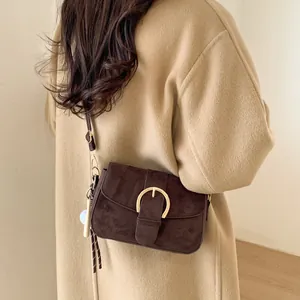 Retro dark brown matte shoulder bag with a large gold buckle on a stylish wool coat