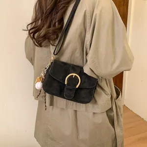 Close-up of black matte shoulder bag with gold horseshoe buckle and creative baseball charm