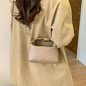 Elegant beige structured crossbody bag with gold lock and vertical leather texture for women