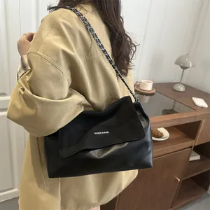 Retro black chain tote bag with white lettering for women worn in a cozy cafe setting