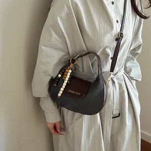 Minimalist round hobo shoulder bag in dark green suede with stylish beaded accessory