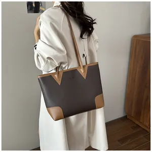 Detail of a large contrast leather tote bag with shoulder straps shown on a model