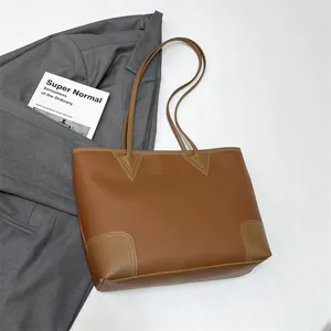 Detailed macro view of brown lychee-textured leather tote bag with reinforced stitching