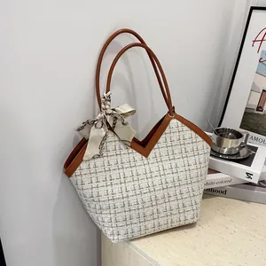 Détail d'un sac cabas en tweed avec garniture en cuir et foulard en soie sur l'anse