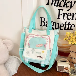 Detail of canvas tote bag showing embroidery and mint green contrast zip pockets