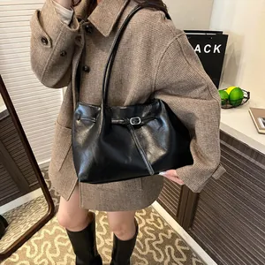 Minimalist black faux leather tote bag with silver buckle strap shown on a model
