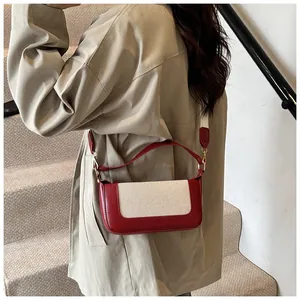 Detail of red leather and beige canvas patchwork bag with a stylish wide shoulder strap