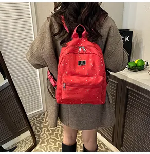 Close-up of red backpack with silver star patterns, metal logo and adjustable straps