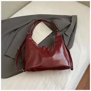 Détail d'un sac hobo en cuir verni bordeaux avec une bandoulière réglable et élégante