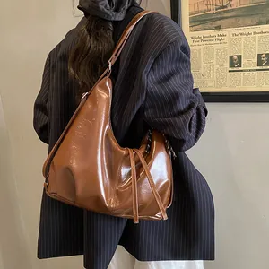 Sac hobo marron en cuir brillant avec franges porté par un mannequin en décor rétro