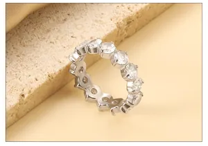 Detailed view of silver eternity ring with zircon stones on travertine stone background