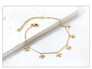 Detailansicht der 18k Gold-Fußkette mit kleinen Flugzeug-Anhängern und Karabinerhaken