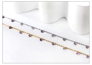 Detail of 18k gold and silver anklets featuring purple crystals on white aesthetic background