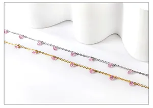 Detail of 18k gold and silver anklets with pink pear-shaped drop zircon charms