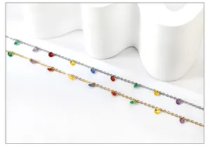 Detail of 18k gold and silver plated anklets featuring colorful crystal charms on white