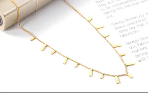 Macro shot of gold rectangle bar pendants on a delicate stainless steel chain necklace