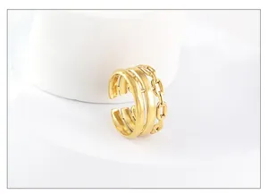 Detailed close-up of triple-layered 18k gold adjustable ring with cuban chain texture