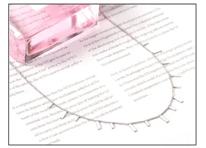 Detailed view of silver bar pendant necklace laid on a book with soft lighting