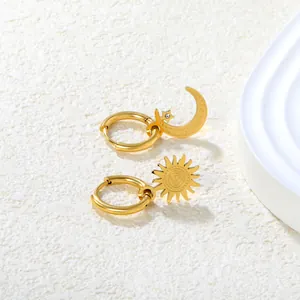 Dettaglio di orecchini asimmetrici in oro a forma di sole e luna con pietre di zircone